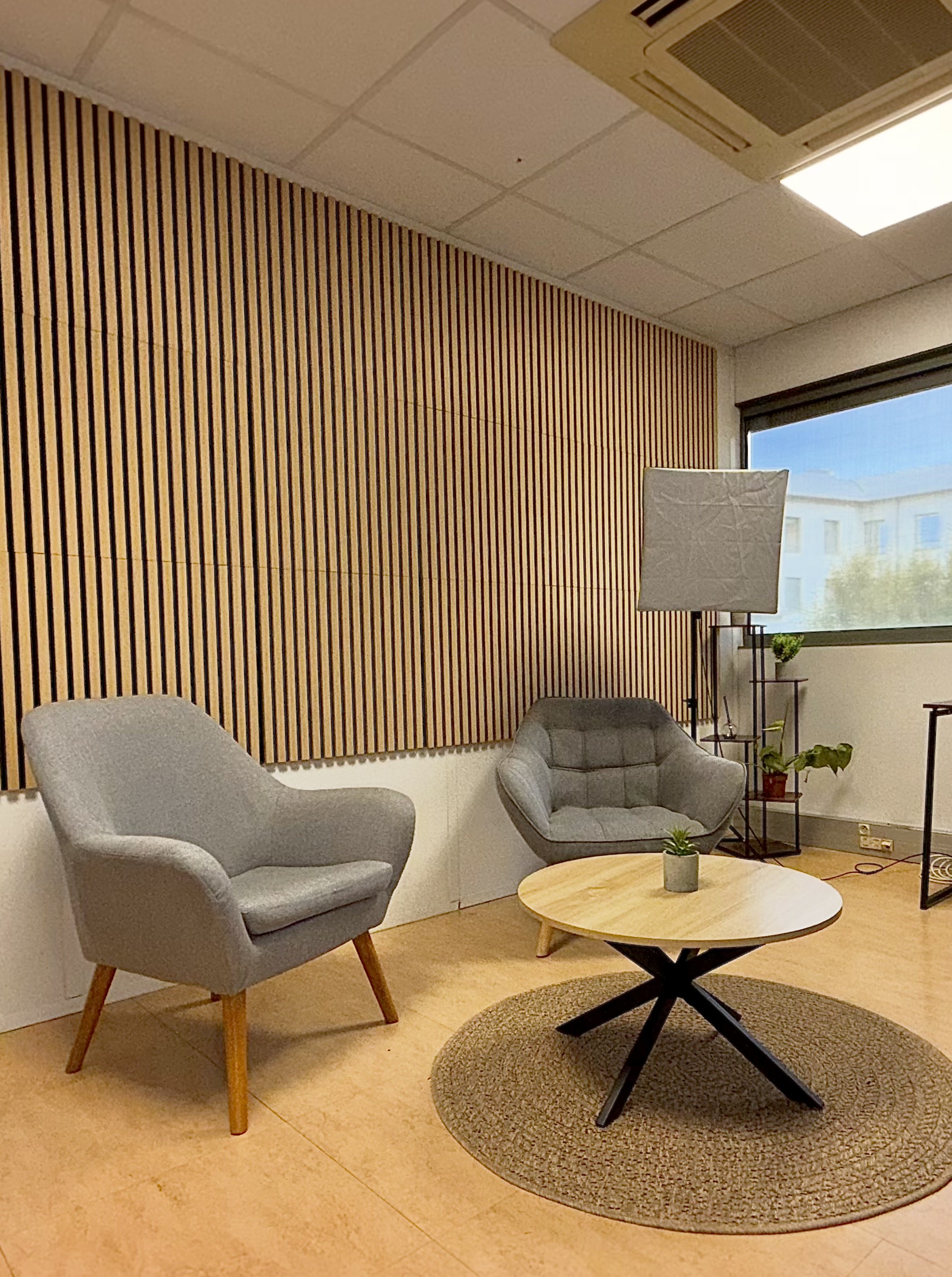 Décor du studio podcast avec fauteuils, table et mur en tasseaux